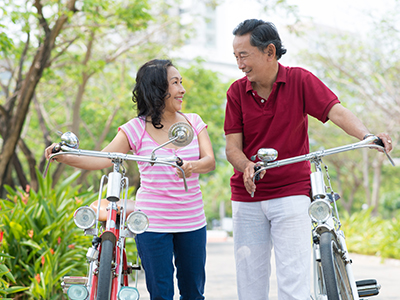 Man and woman walking with their bicycles outdoors