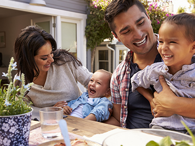 Couple sitting at an outdoor table with a baby and toddler