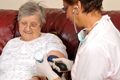 امرأة تخضع لفحص ضغط الدم من قبل أخصائي رعاية صحية.