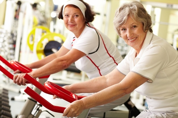 Foto de dos sonriendo a las mujeres de mediana edad en bicicletas de ejercicio