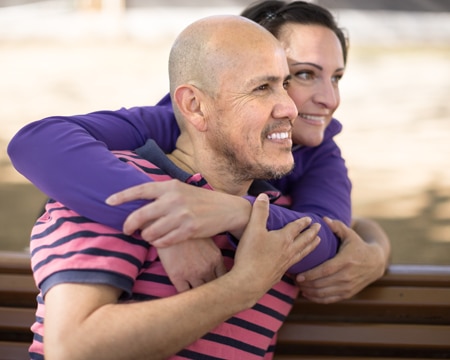 A couple embraces on park bench.