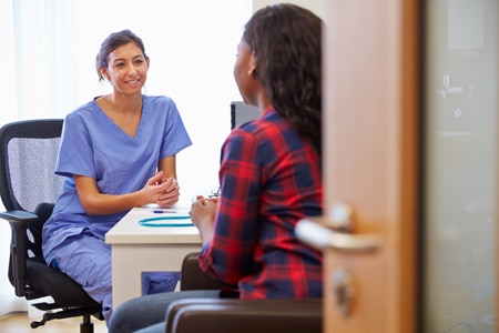 A health care professional speaks to a woman.