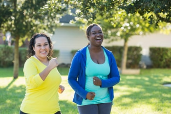 Two women power-walking outdoors.