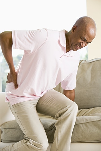 Man standing up from sitting with a hand on his painful hip.