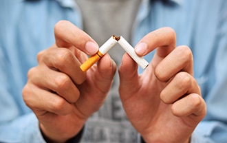 Man breaking a cigarette in half.