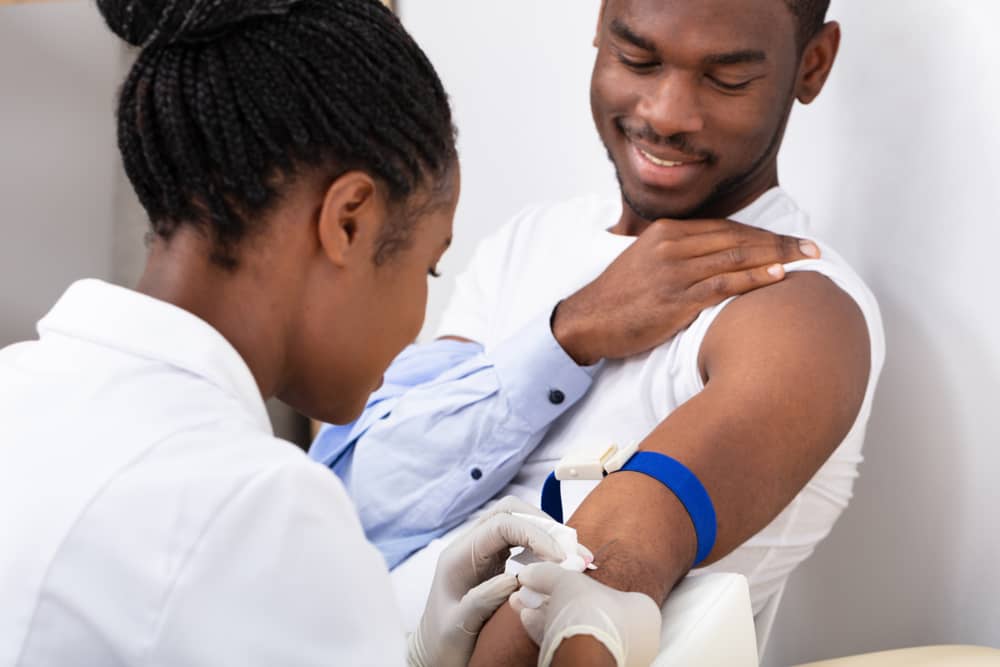 Profesional del cuidado de la salud extrayendo sangre del brazo de un paciente.