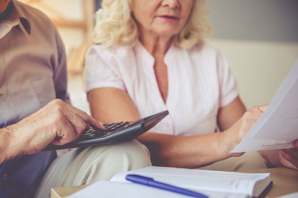 A couple reviewing paperwork and typing into a calculator.