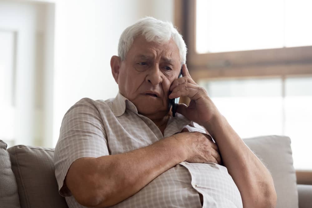 رجل كبير السن مع التعبير القلق يجري مكالمة هاتفية.