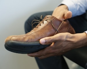 Photo of a man feeling inside his shoe.