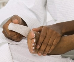 Photo of a woman smoothing the bottom of her foot with a pumice stone.