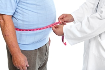 Health care professional measures a man’s waistline.