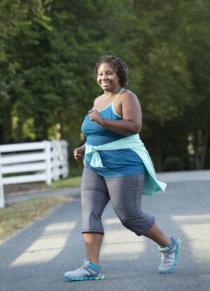A woman who is overweight walking in athletic clothes.