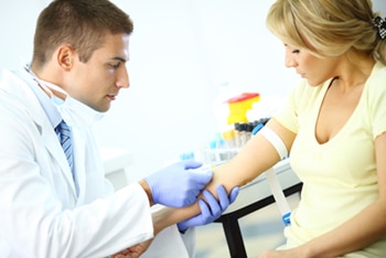 أخصائي رعاية صحية يسحب دم مريضة لفحص الدم.