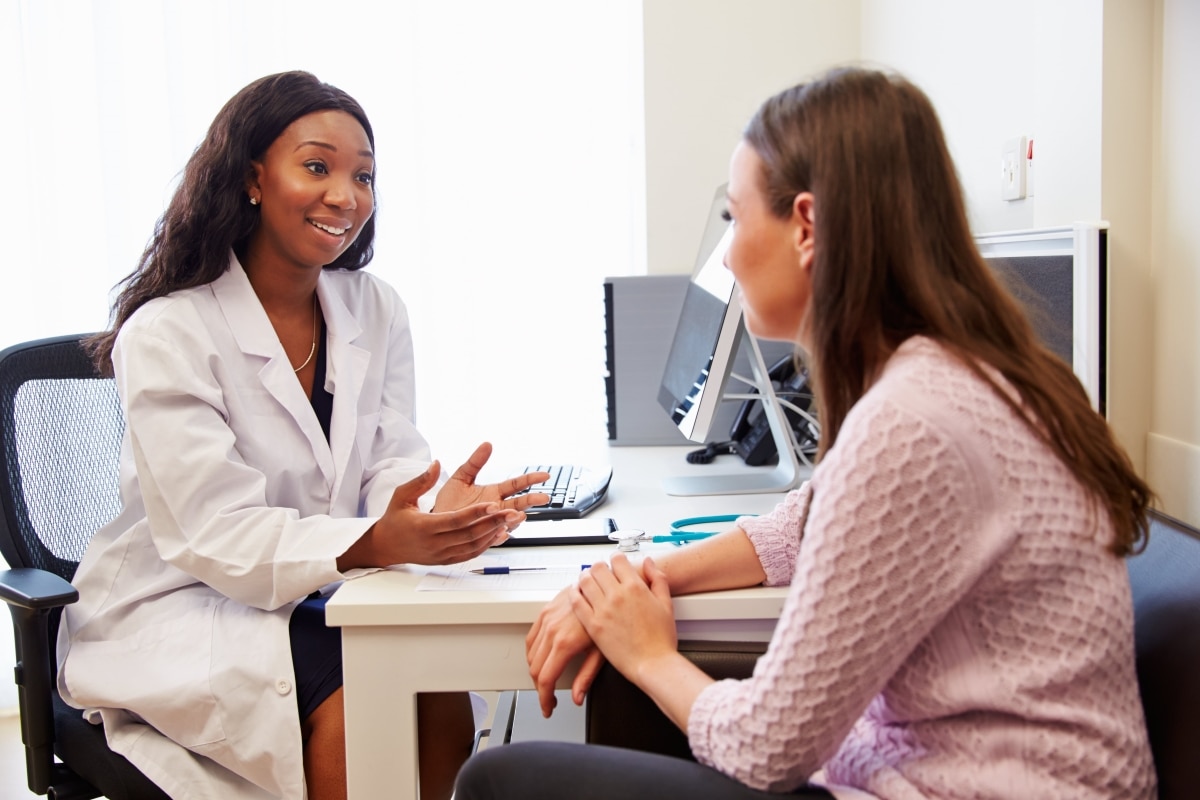 Una profesional de atención médica habla con una paciente.