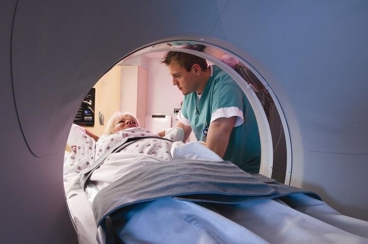 Vista desde el interior del túnel de la resonancia magnética, con una paciente hablando con un profesional de atención médica.