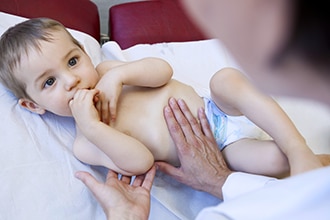 A doctor feels a young child’s abdomen.