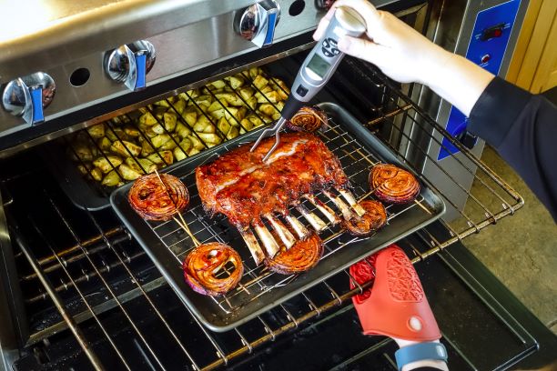 uma pessoa usando um termómetro de carne para medir a temperatura interna da carne.