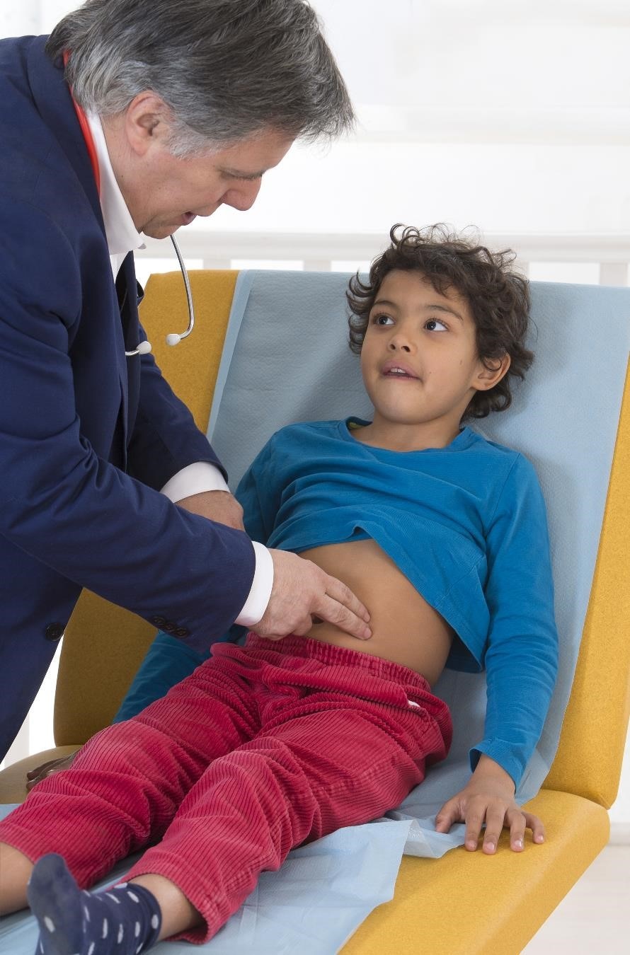 يقوم الطبيب بفحص بطن الطفل أثناء الفحص البدني.