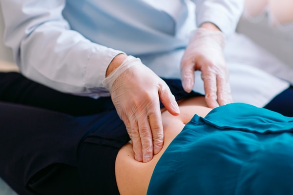 A doctor’s fingers pressing on a patient’s abdomen.