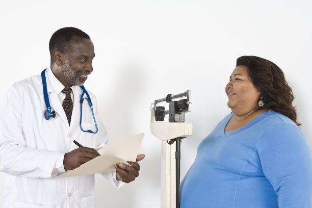 Un médico tomando nota del peso de una paciente obesa.
