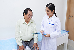 Female nurse speaking to gentlemen and going over medical charts.