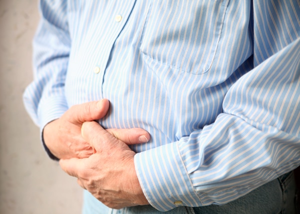 Man holding both hands to his belly.