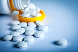 Pills and a pill bottle on its side on top of a table.