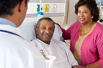 A health care professional speaking to a patient and his wife in a hospital setting.