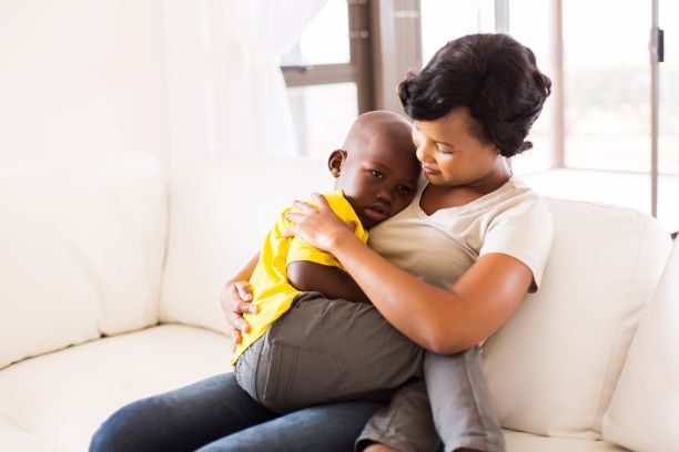 A sick boy sitting on his mother’s lap.