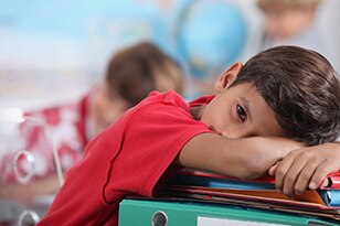 Child with head down on school desk