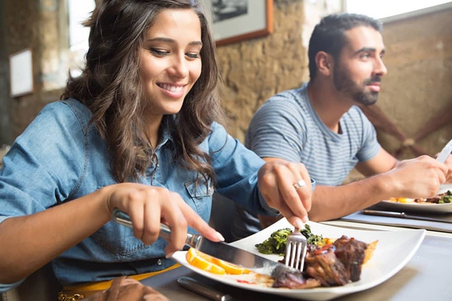 Smiling woman eating dinner in a restaurant.