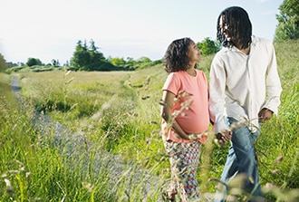 A pregnant woman and man walk on a path.