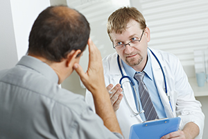 A male doctor talking with male patient about symptoms of proctitis.