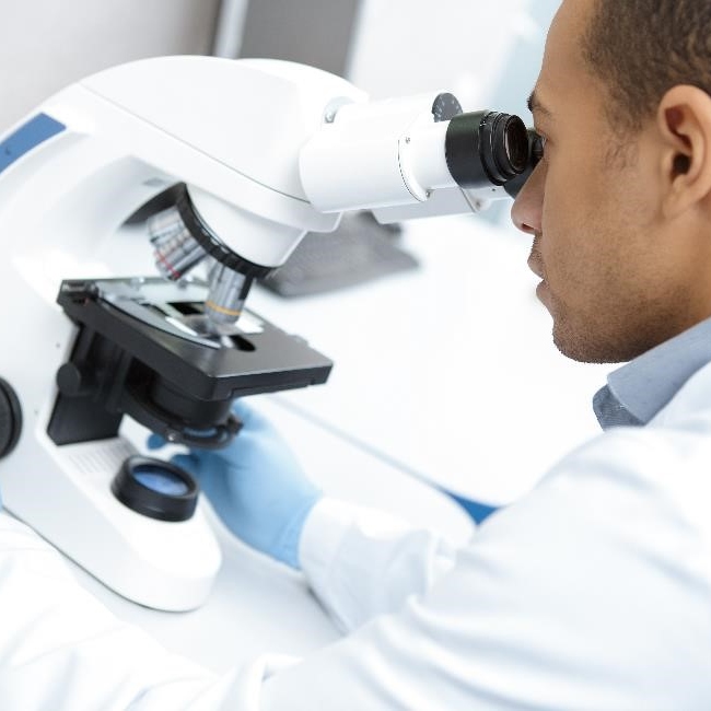 Health care professional using a microscope.