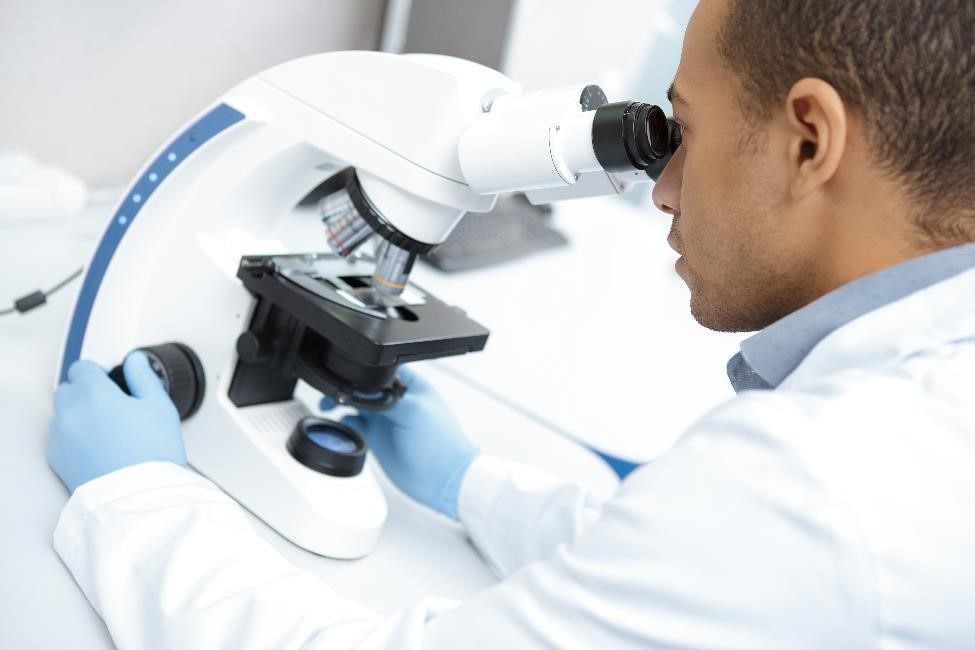 Health care professional using a microscope.