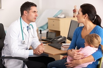 A doctor talking with a mother holding her child.