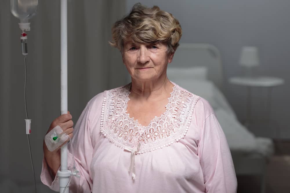 A hospital patient walking while holding an IV pole.