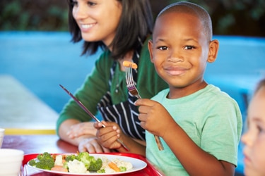 A young boy sitting at a table eating.