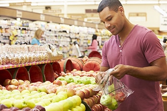 A man shops at a grocery store for fruit.