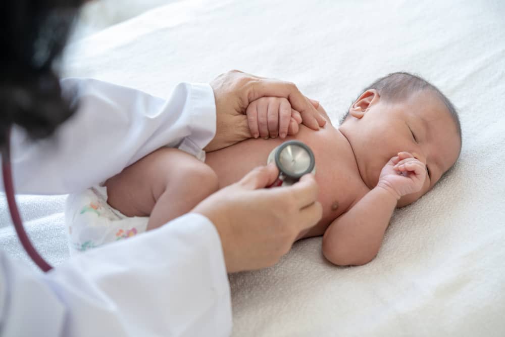 A doctor examines an infant’s belly for swelling.