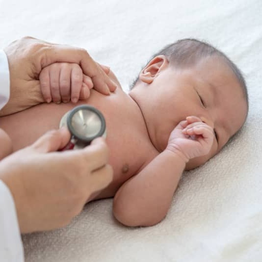 A doctor examines an infant’s belly for swelling.