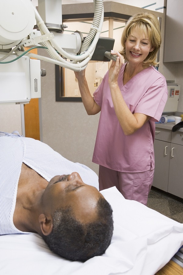 Technician sets up x-ray machine and patient lies on x-ray table.