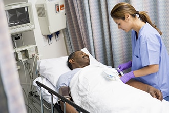 A man lying on a hospital bed prepares for surgery with a health care professional.