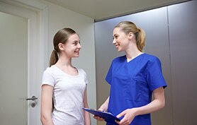 Nurse talking to a patient in a hospital hallway.
