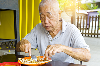 An older man eating a meal.