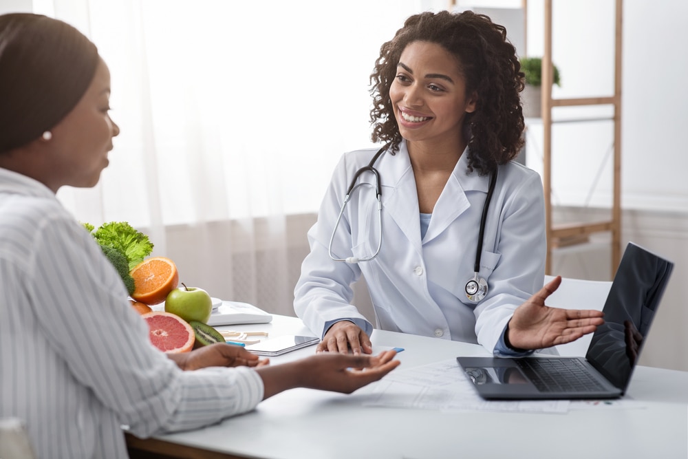 Una médica y una paciente hablando en un consultorio.