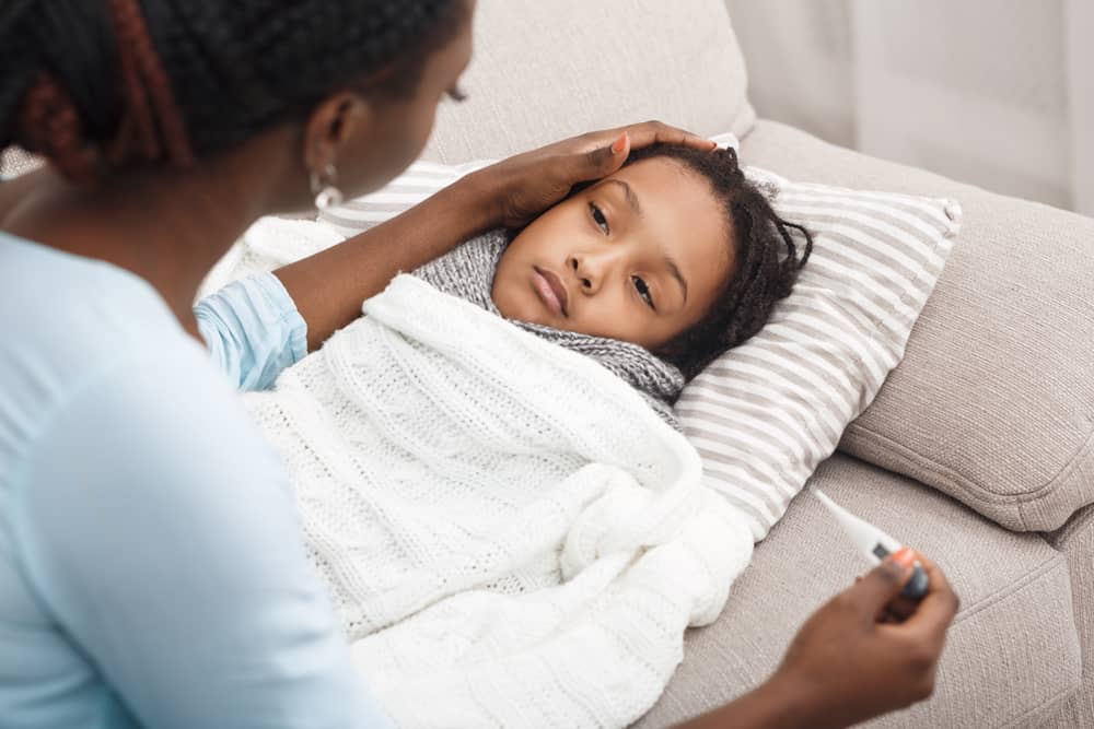 Una madre toma la temperatura de su hija con un termómetro digital.