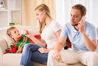 Parents sitting with a sick boy and calling a doctor.