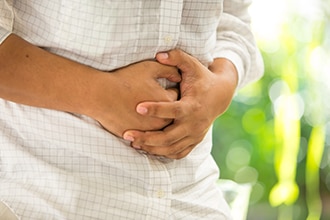 Mains serrant un abdomen dans la douleur.