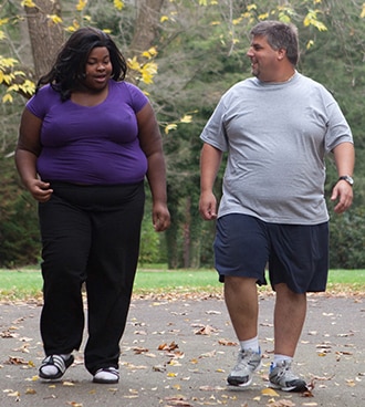 An overweight woman and man taking a walk.